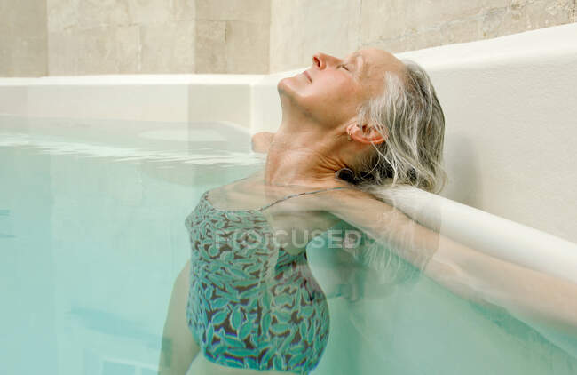 Mujer mayor relajándose en la piscina - foto de stock