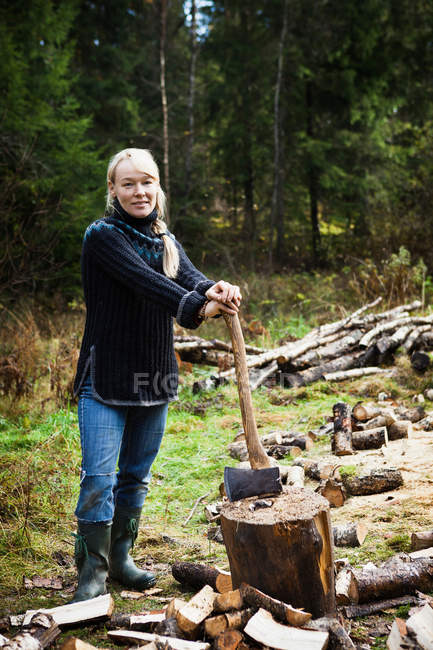 Femme coupant du bois de chauffage dans la forêt — Photo de stock