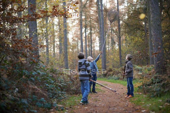 Niños caminando por el bosque con equipo de pesca - foto de stock