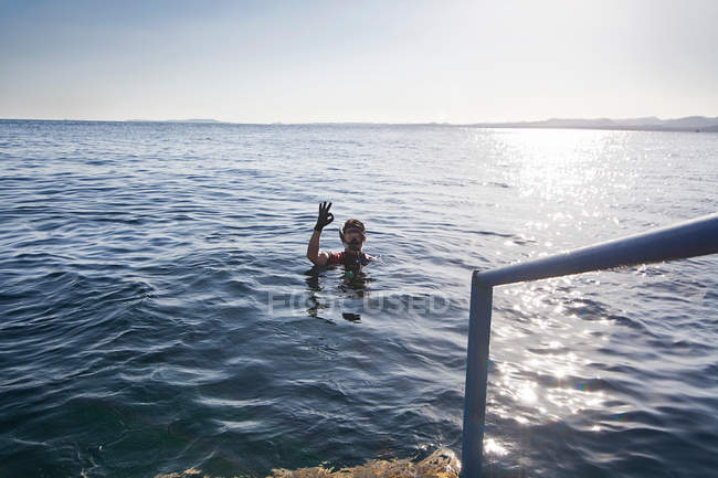 Snorkeler haciendo señal OK en el agua - foto de stock