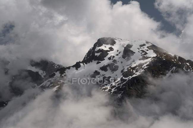 Nuages et montagne enneigée — Photo de stock