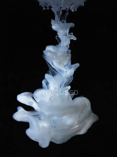 Milk fading in water on black background — Stock Photo