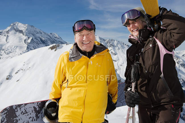 Mature couple in ski-wear holding Skis — Stock Photo