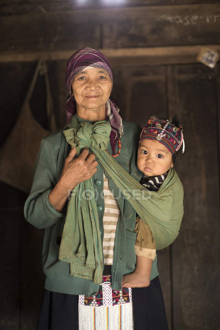 Portrait of grandmother holding baby boy in sling, Shan State, Keng Tung, Burma — Stock Photo