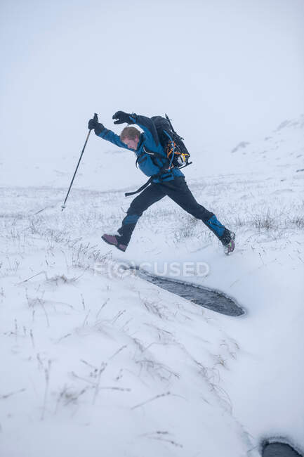 Hiker jumping in snowy landscape — Stock Photo