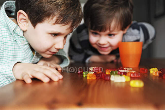 Хлопчики грають з цукерками за столом — стокове фото