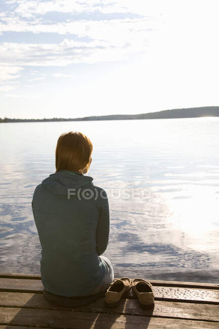 Donna seduta sul molo — Foto stock