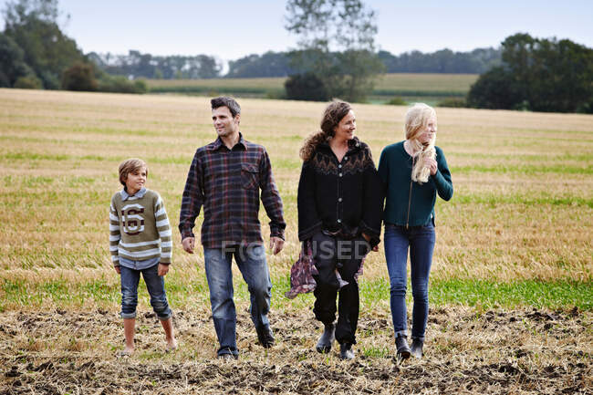 Família caminhando juntos no campo gramado — Fotografia de Stock