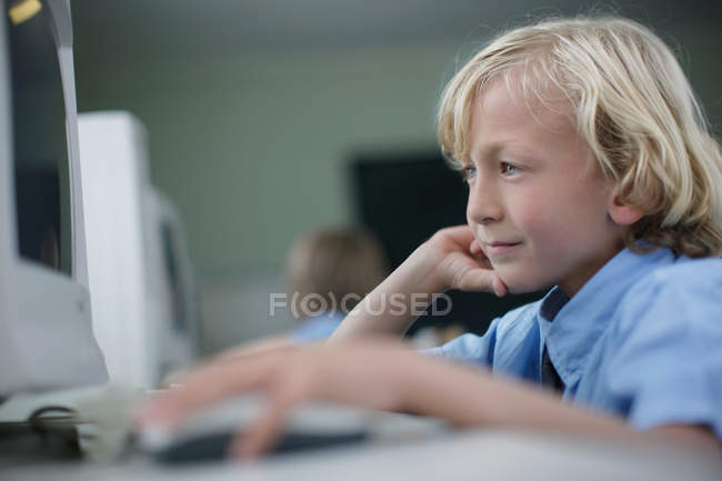 Niño de la escuela usando computadora - foto de stock