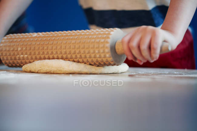Hands rolling dough with studded pin — Stock Photo
