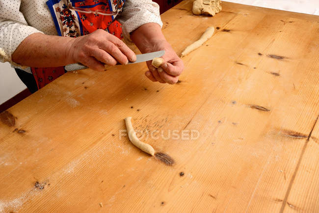 Abgeschnittenes Bild einer Seniorin, die zu Hause Pasta aus Teig macht — Stockfoto