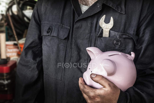 Teilansicht aus nächster Nähe: Arbeiter hält Sparschwein — Stockfoto