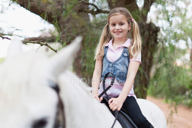 Chica sonriente a caballo en el parque - foto de stock
