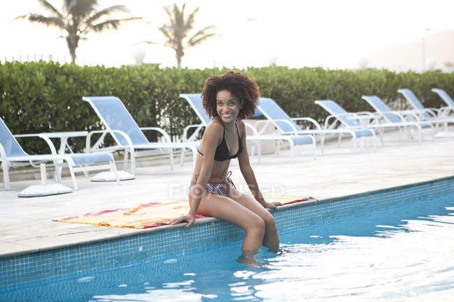 Giovane donna in bikini seduta a bordo piscina dell'hotel, Rio De Janeiro, Brasile — Foto stock
