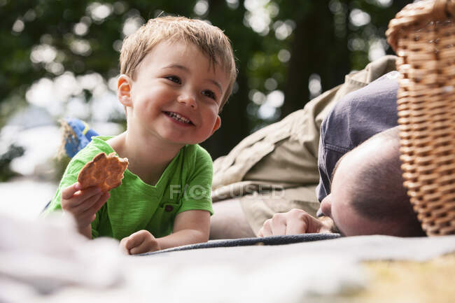 Chico disfrutando de picnic con padre - foto de stock