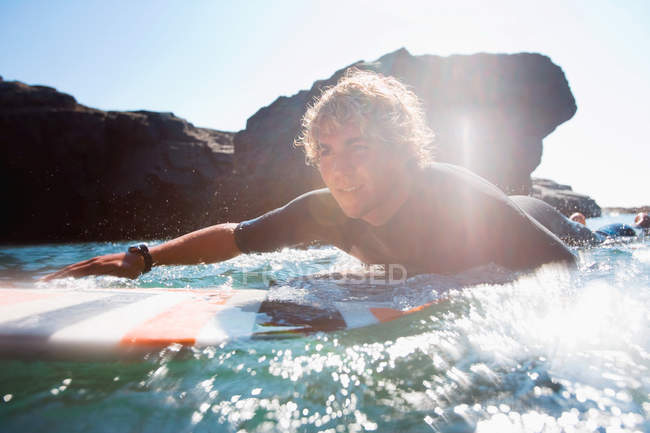 Homem deitado na prancha de surf na água — Fotografia de Stock