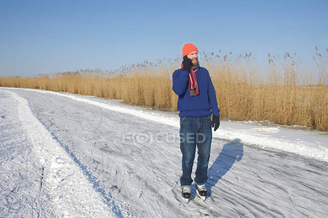 Man in ice skates talking on cell phone — Stock Photo
