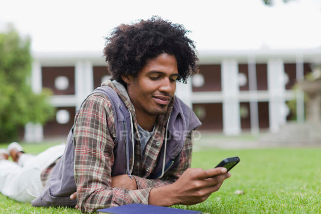 Студент использует мобильный телефон на траве — стоковое фото