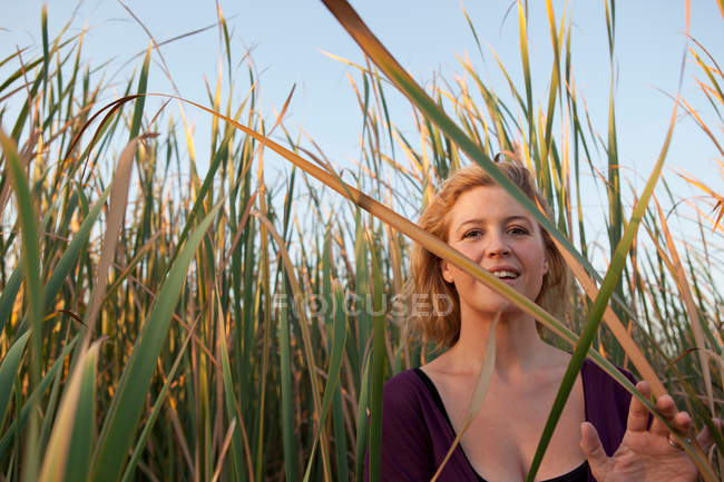 Lächelnde Frau steht im Weizenfeld — Stockfoto