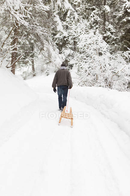 Homem puxando trenó no campo nevado — Fotografia de Stock