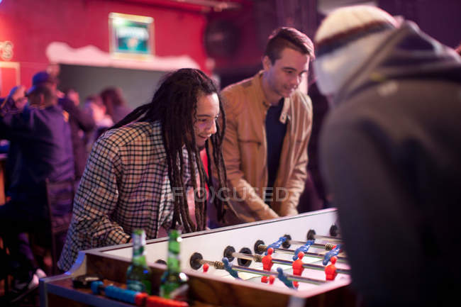 Hombres jugando fútbol de mesa en el bar - foto de stock