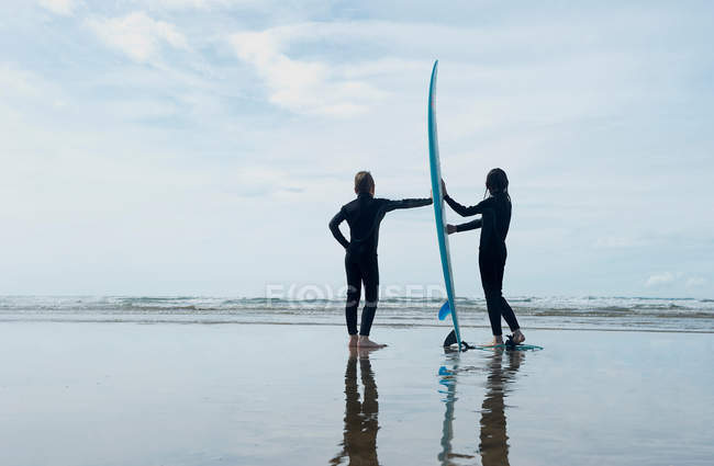 Дети держат доску для серфинга на пляже — стоковое фото