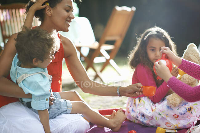 Madre e hijos jugando picnics en la fiesta de cumpleaños del jardín - foto de stock