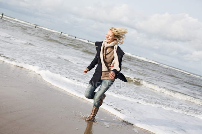 Lächelnde Frau läuft am Strand — Stockfoto