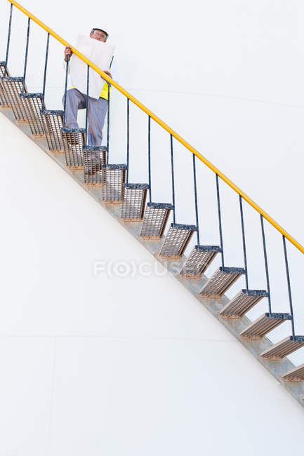 Worker climbing steps at chemical plant — Stock Photo