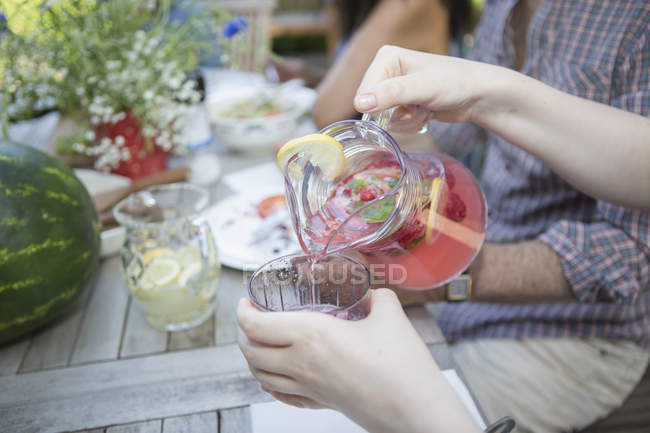 Woman pouring home-made drink to glass — Stock Photo