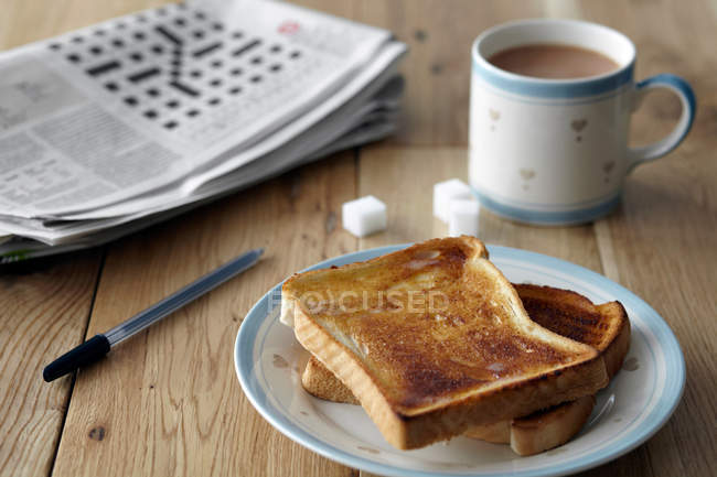 Кросворд з тостами та чаєм на столі — стокове фото