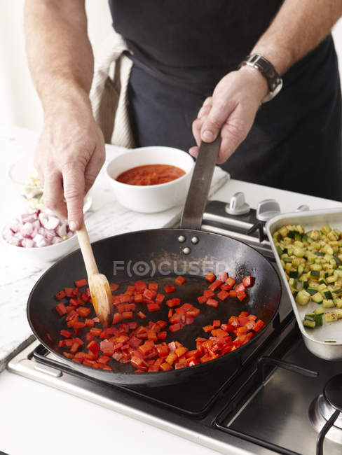 Hombre freír pimientos rojos - foto de stock