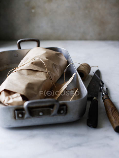 Meat wrapped in butchers paper in baking tin — Stock Photo