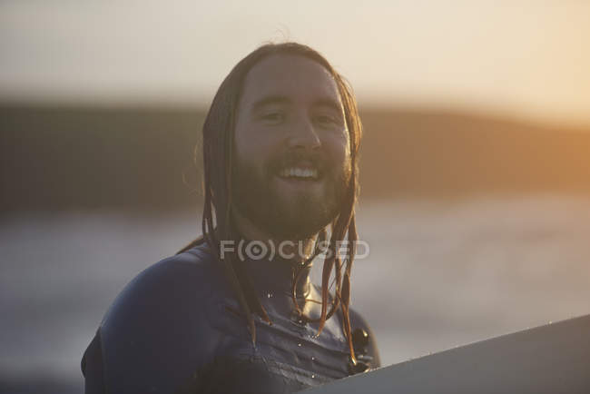 Portrait of young male surfer carrying surfboard, Devon, England, UK — Stock Photo