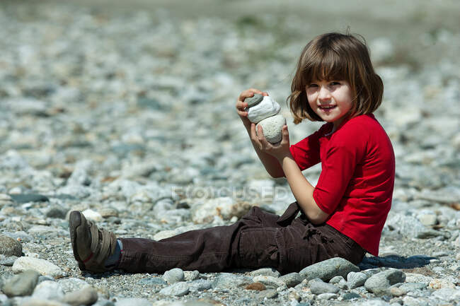 Девушка играет со скалами на пляже — стоковое фото