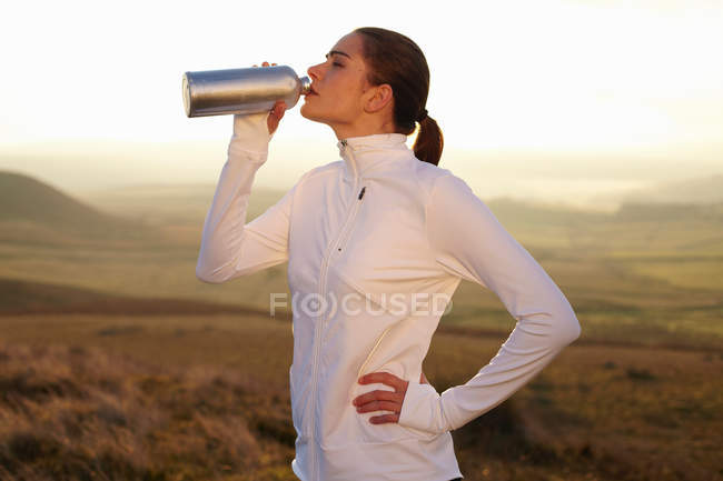 Бігун п'є воду в сільському пейзажі — стокове фото