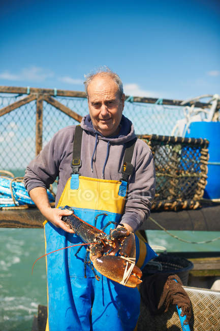 Fisherman holding lobster on boat — Stock Photo