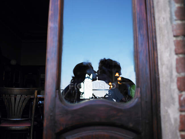 Reflection of couple kissing in caf?. — Stock Photo