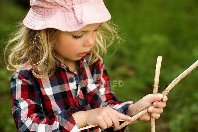 Menina brincando com paus ao ar livre — Fotografia de Stock