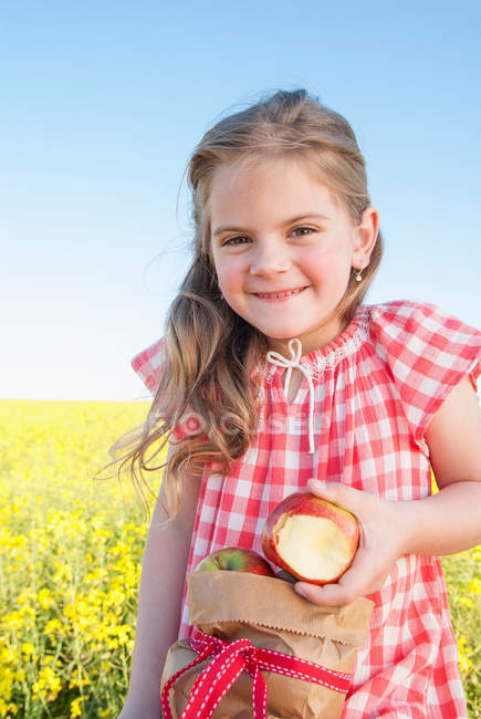 Chica comiendo saco de manzanas al aire libre - foto de stock
