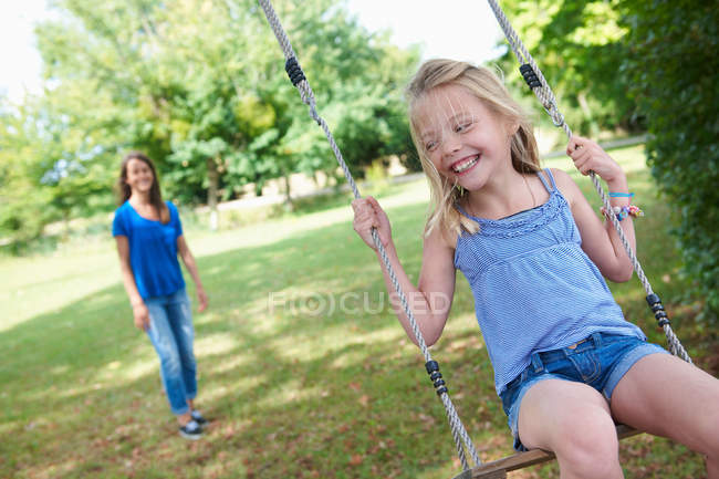 Дівчина грає на гойдалках на задньому дворі, вибірковий фокус — стокове фото