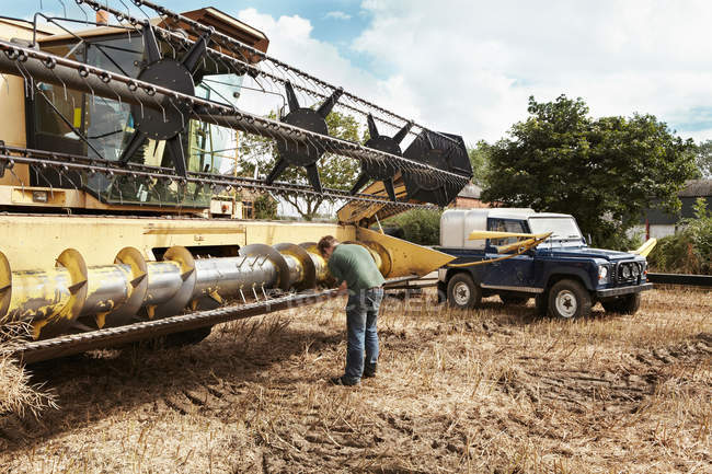 Farmer examining thresher on farm — Stock Photo