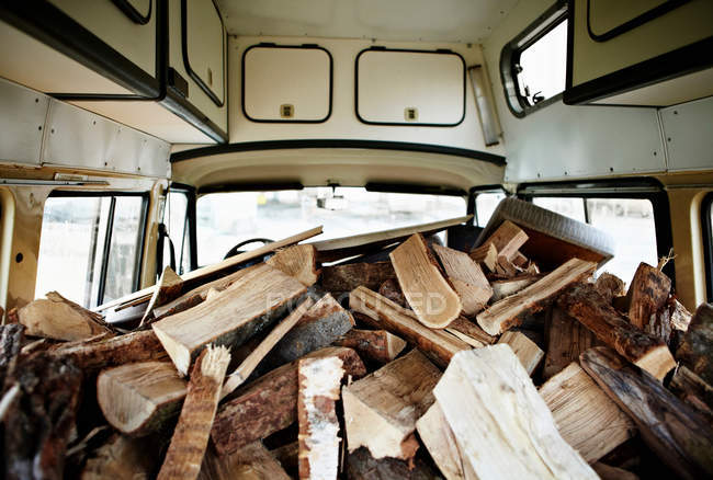 Chopped logs and firewood piled in van — Stock Photo