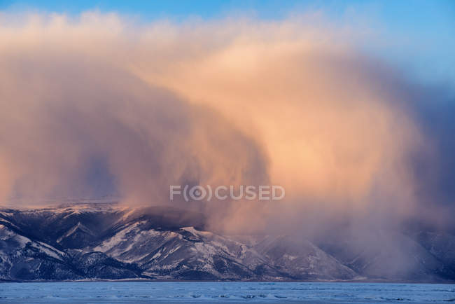 Nuages de tempête bas roulant sur des montagnes enneigées — Photo de stock