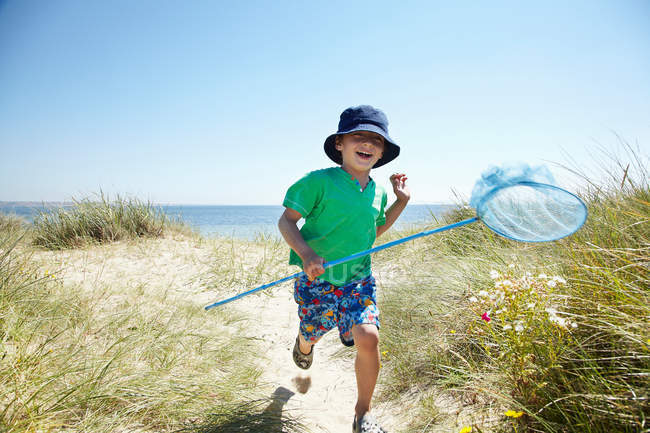 Junge trägt Fischernetz am Strand — Stockfoto