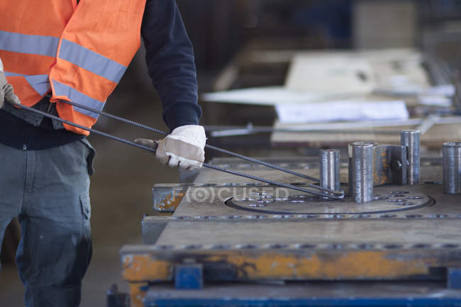 Fábrica trabalhador dobra haste de metal na fábrica de reforço de concreto — Fotografia de Stock