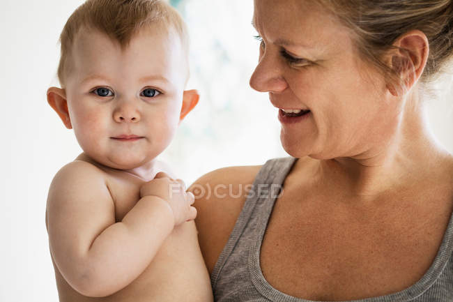 Mère souriante tenant bébé fille — Photo de stock