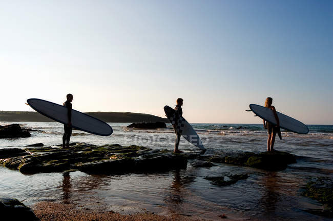 Three people holding surfboards standing — Stock Photo