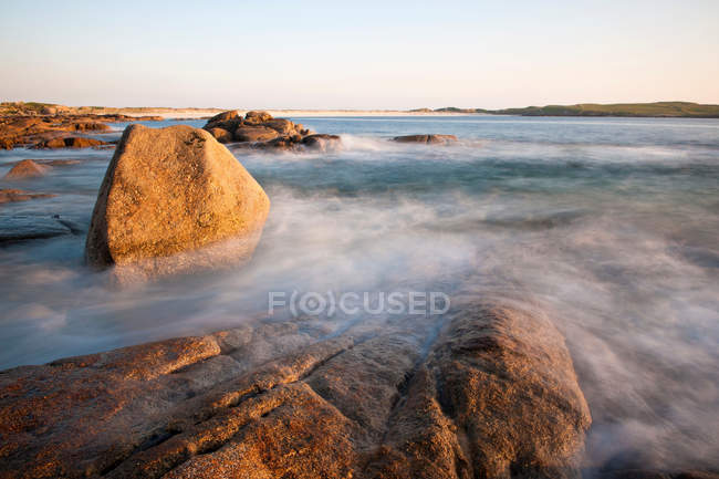 Ondas lavándose en la playa rocosa - foto de stock