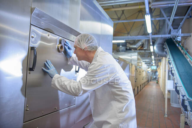 Worker inspecting oven used to bake biscuits in food factory — Stock Photo